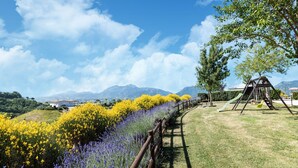 A playground with a swing set and slide, surrounded by fields of yellow and purple flowers, with mountains in the background. - Country House in Marche with Pool & Views (Cagli)