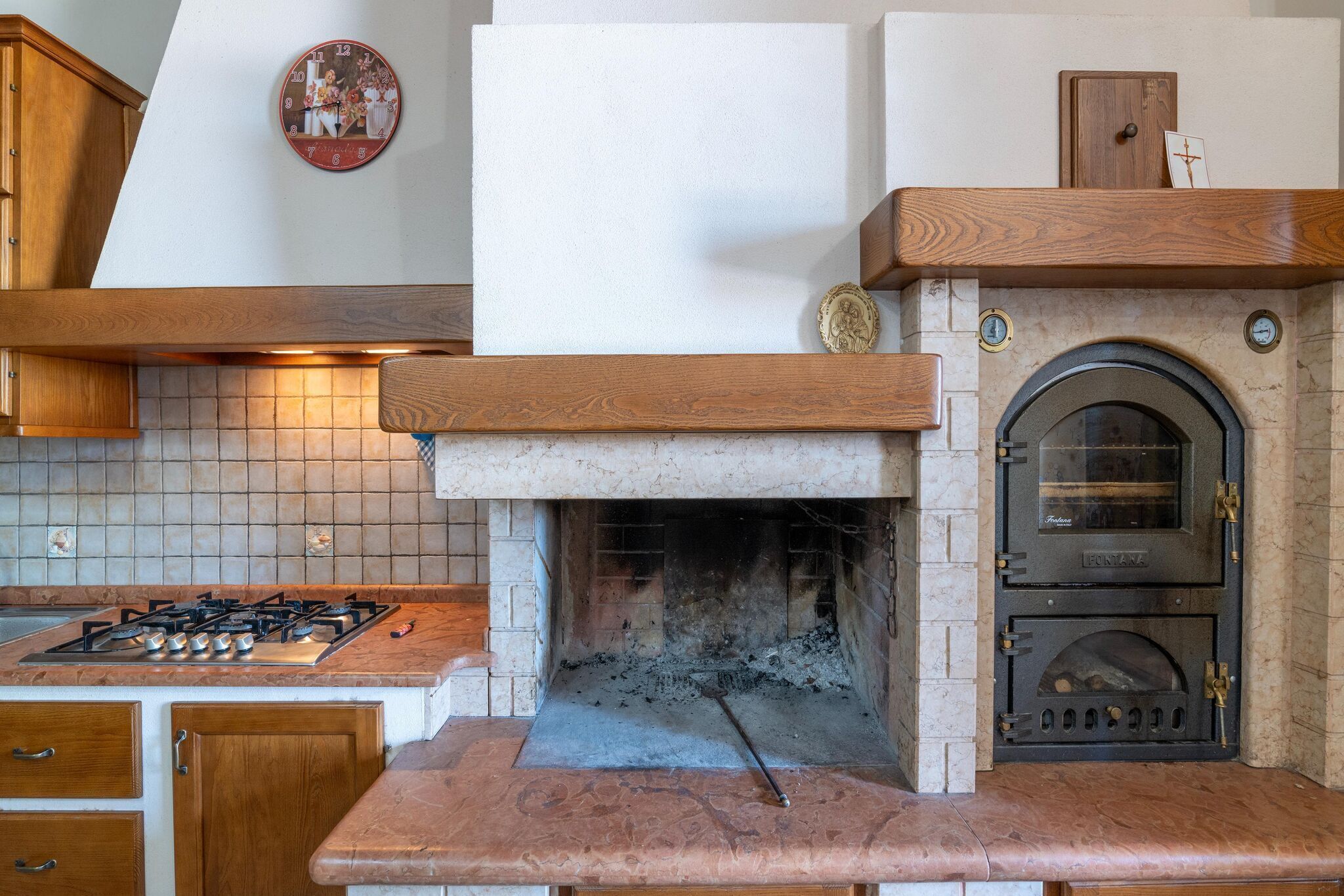 A kitchen with a built-in wood-burning stove, a tiled backsplash, and wooden cabinets.