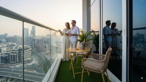 Ein moderner Balkon mit Blick auf die Stadt, ein kleiner Tisch mit Stühlen und ein Blumentopf.