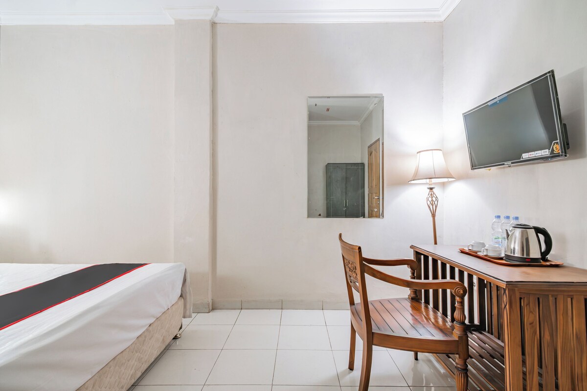 Una habitación de hotel con una cama, un escritorio con silla, un televisor y una lámpara.