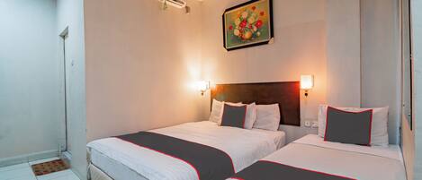 A hotel room with two beds, a painting on the wall, and an air conditioning unit.