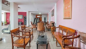 Eine geräumige Lobby mit hölzernen Bänken, einer Treppe und einem großen, gerahmten Bild an der Wand.