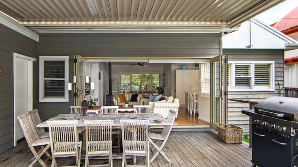 A covered outdoor dining area with a table and chairs, a grill, and a view into the house. - Diamond Retreat by HolidayCo. (PEARL BEACH)