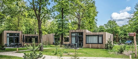 A modern wooden cabin with large windows, outdoor seating, and a well-maintained garden.