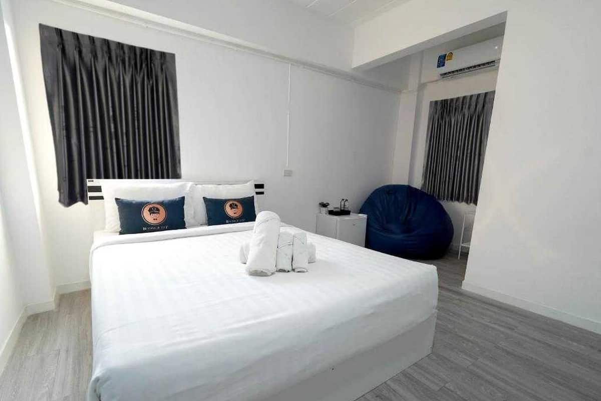A modern hotel room with a large bed, a desk, and a bean bag chair.