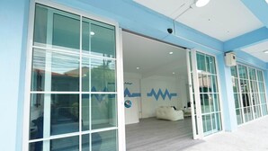 Un edificio moderno con grandes puertas de vidrio, una recepción con un sofá y un logotipo en la pared.