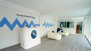 Un moderno vestíbulo de hotel con mostrador de recepción, un amplio espacio de asientos y un gran ventanal que proporciona luz natural.