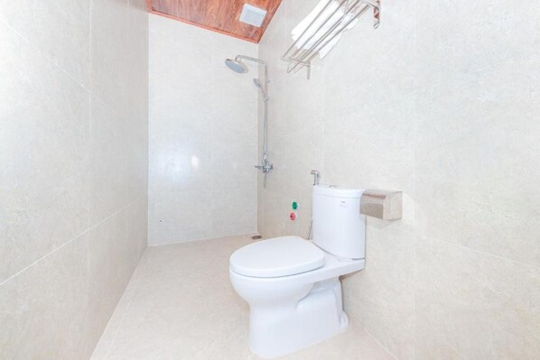 A small, clean bathroom with a toilet, a shower, and a towel rack. - Hoàng Sa Bãi Dài (Cam Lam)