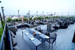 An outdoor seating area with multiple tables and chairs, arranged in a semi-circular fashion.