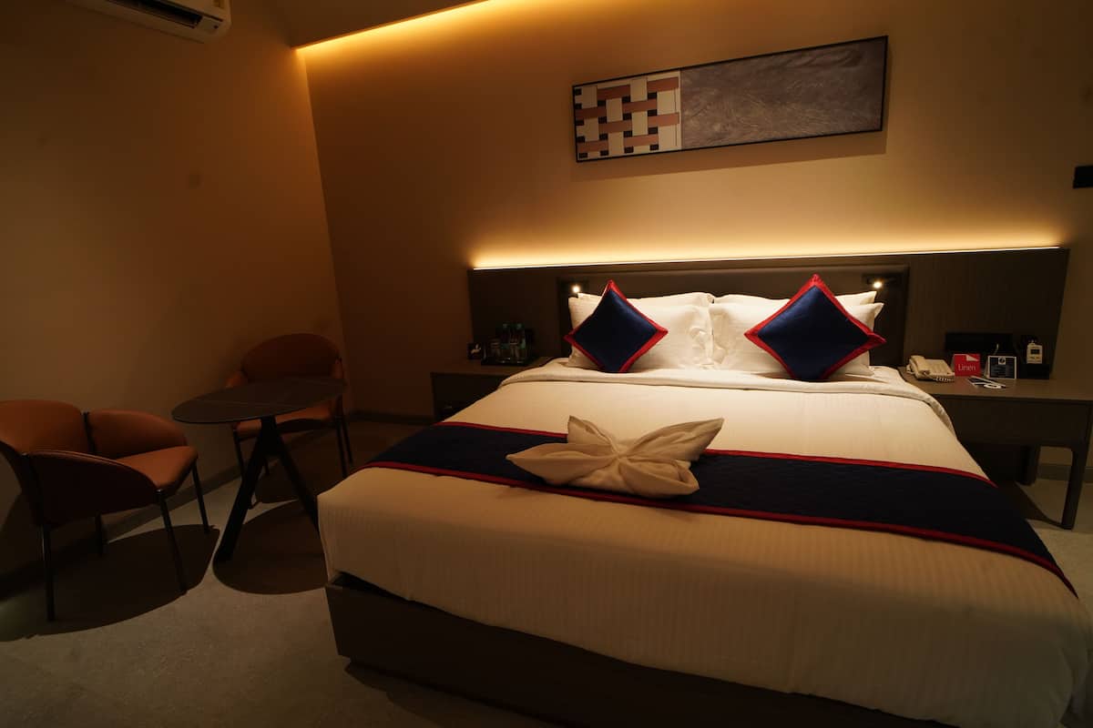 Une chambre d’hôtel avec un lit bien fait, une petite table ronde et deux chaises.