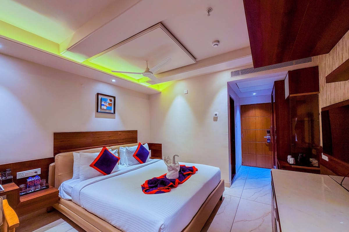 Quarto de hotel com cama, mesa de cabeceira e ventoinha no teto.