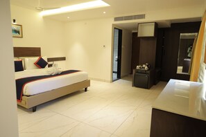 Habitación de hotel con una cama, un escritorio pequeño, un espejo y una puerta que da a un baño.