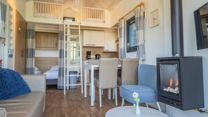A cozy interior with a loft bedroom, a dining area, and a living space featuring a wood-burning stove. - Pet-friendly Getaway in North Holland (West-Graftdijk)