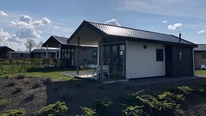 En envåningsbyggnad med en täckt uteplats, en liten trädgård och en klar himmel med moln.