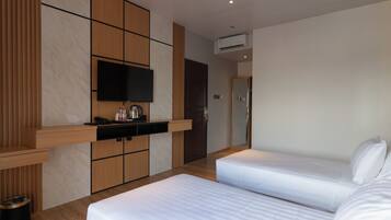 Una habitación de hotel moderna con dos camas, un televisor de pantalla plana, un minibar y un panel de pared de madera.