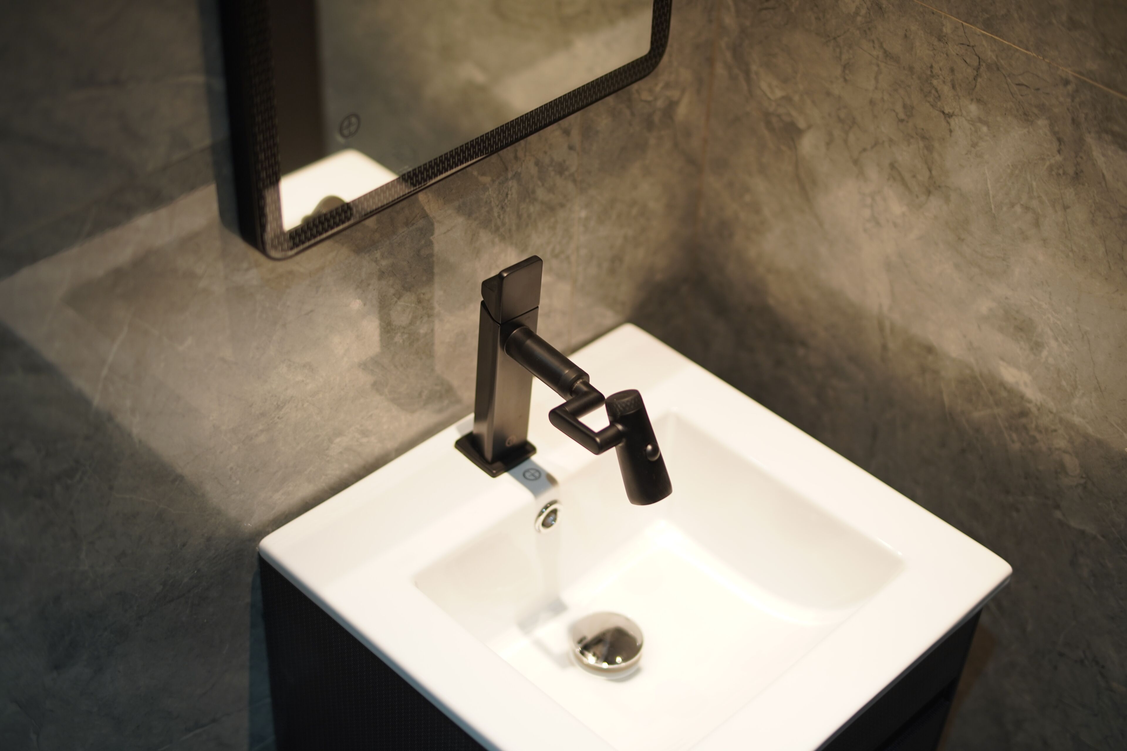 A modern bathroom sink with a rectangular basin, a single faucet, and a mirror above it.