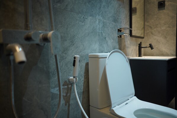 A modern bathroom with a toilet, a shower, and a sink.