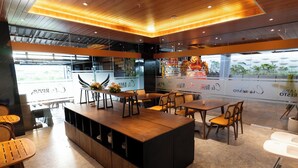 A modern restaurant with wooden furniture, a central island, and large windows offering a view of the outdoors. - Eagle Hotel Wonosobo, Azana Hotels Collection (Wonosobo)