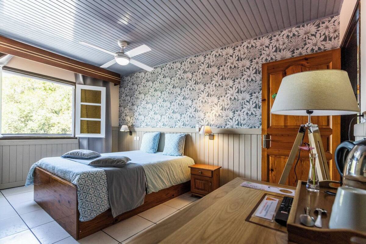 Een slaapkamer met een bed, nachtkastje, lamp en uitzicht op de omgeving.