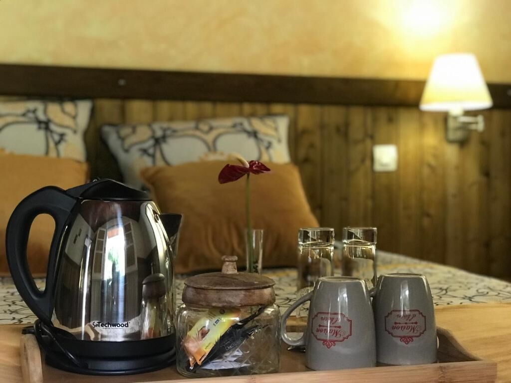 A wooden bedside table with a kettle, a glass jar, two mugs, and a decorative item.