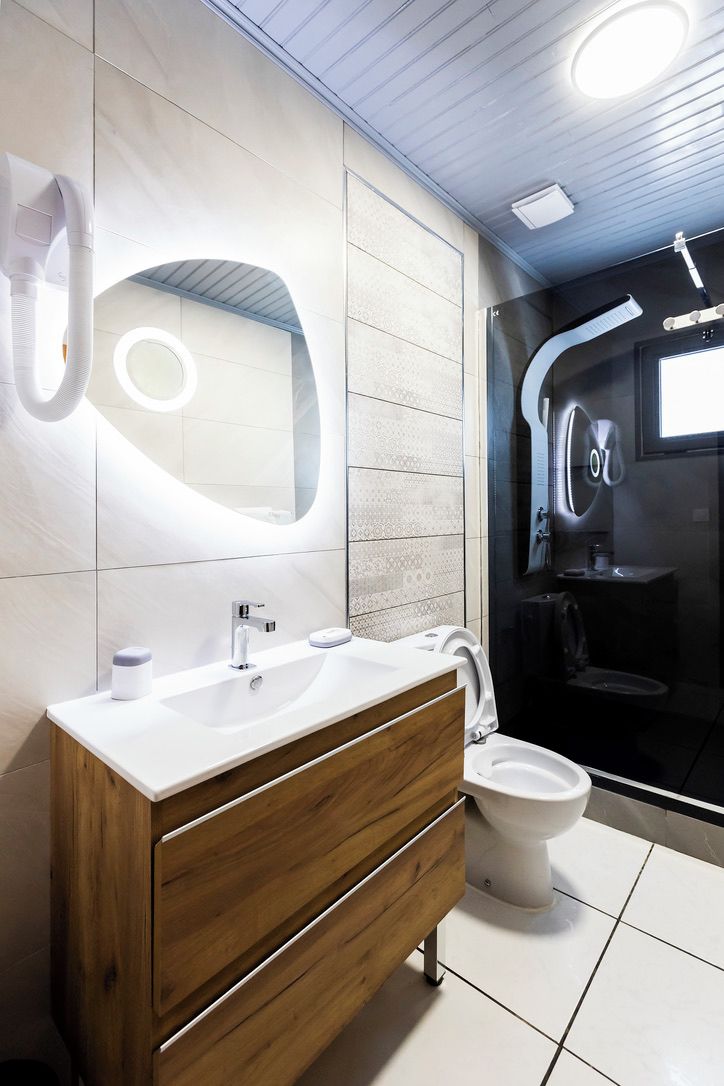 A modern bathroom with a wooden vanity, a large mirror, and a glass-enclosed shower area.