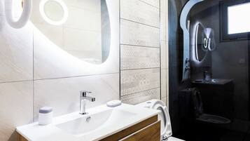 A modern bathroom with a wooden vanity, a large mirror, and a glass-enclosed shower area.