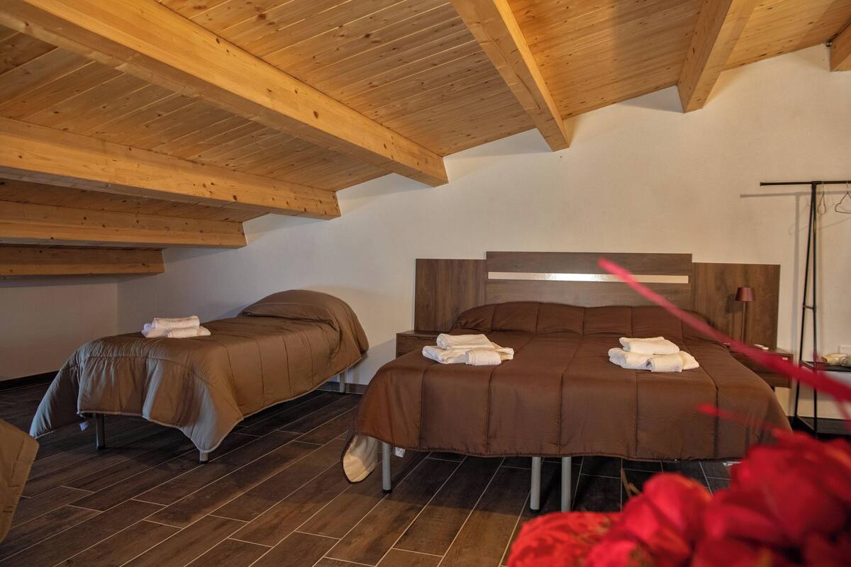 A bedroom with two beds, wooden ceiling beams, and a modern headboard.