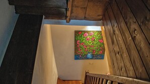 Una escala de fusta amb barana que condueix a una habitació amb un quadre floral a la paret.