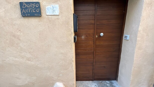 Una porta de fusta amb un petit escaló que hi mena, una closca de correu i un rètol que diu "Borgo Antico" amb un número de telèfon.