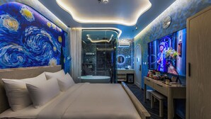 Un dormitorio moderno con una cama grande, un tocador con espejo y un televisor en la pared.