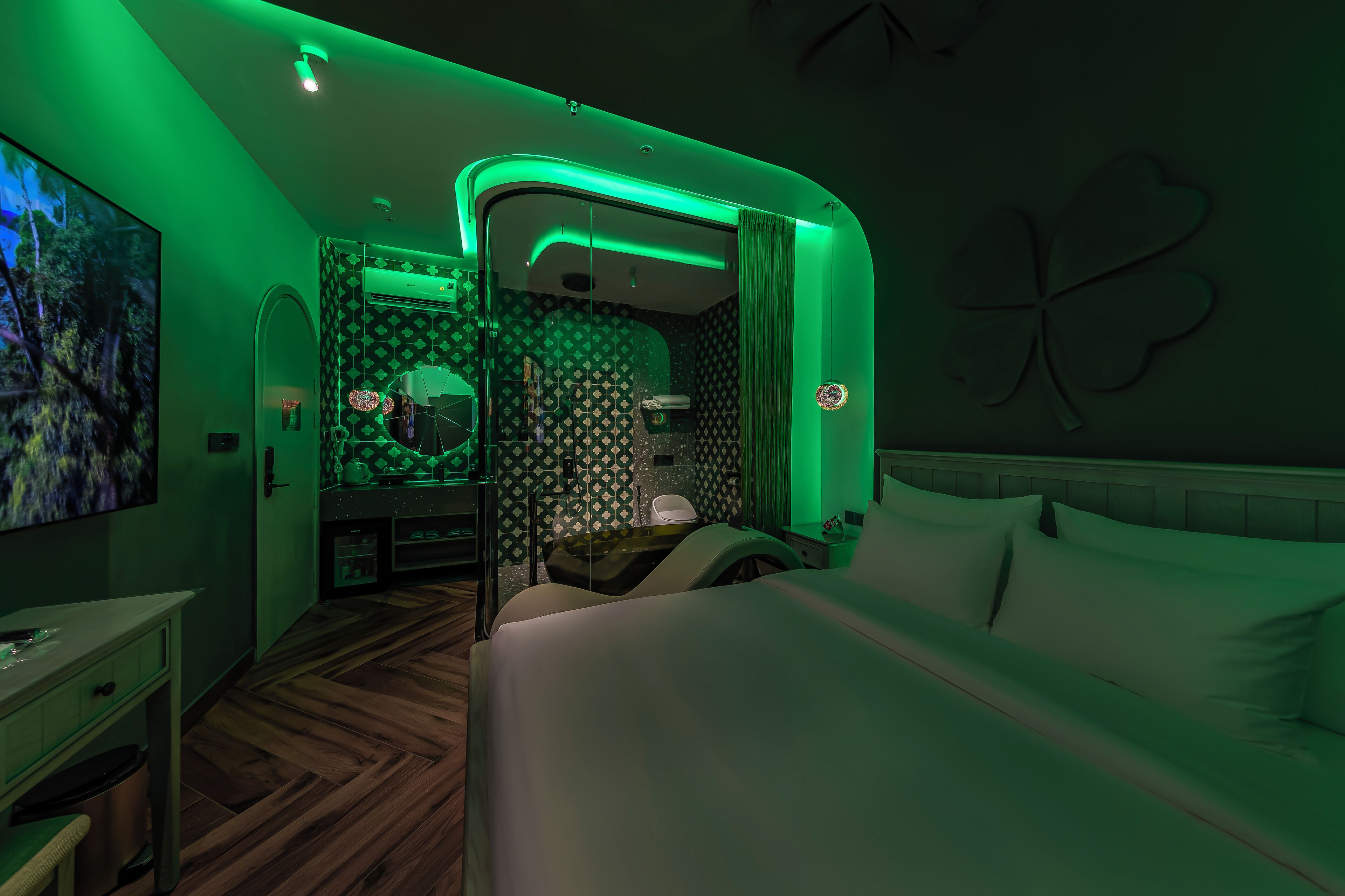 A hotel room with a bed, a desk, a mirror, and a bathroom.