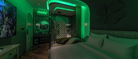 A hotel room with a bed, a desk, a mirror, and a bathroom.