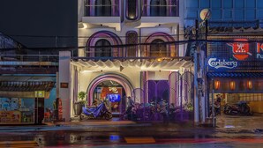 Um edifício com várias andares, varandas e um letreiro de neon.