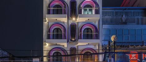 Un immeuble à plusieurs étages, doté de balcons et d'une enseigne lumineuse au néon.