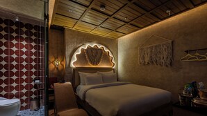 Quarto de hotel moderno com uma cama grande, um espaço de estar, um banheiro e uma parede com um padrão circular único.