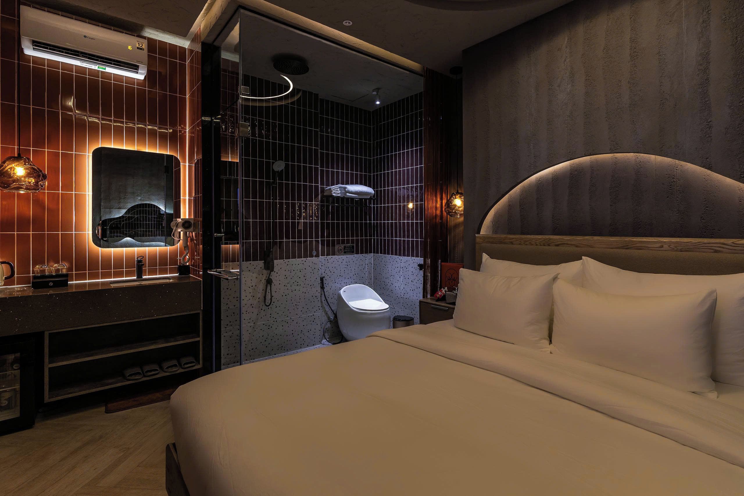 Une chambre d’hôtel moderne avec un grand lit, une salle de bain avec douche et une coiffeuse avec miroir.