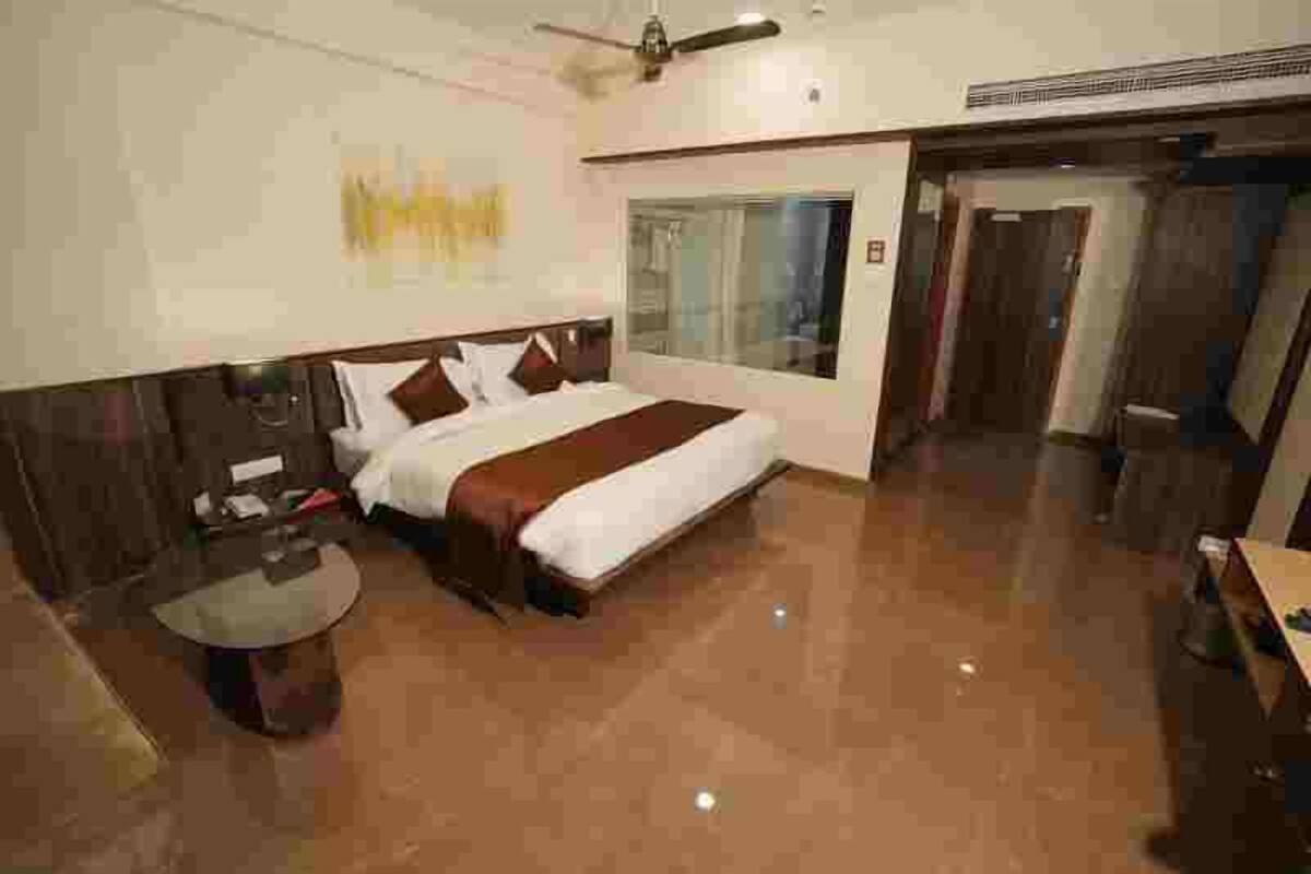A hotel room with a large bed, a round table, and a ceiling fan.