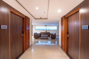 Pasillo de hotel con puertas de madera numeradas 526 y 525, que conduce a un área de descanso con vista a la ciudad.