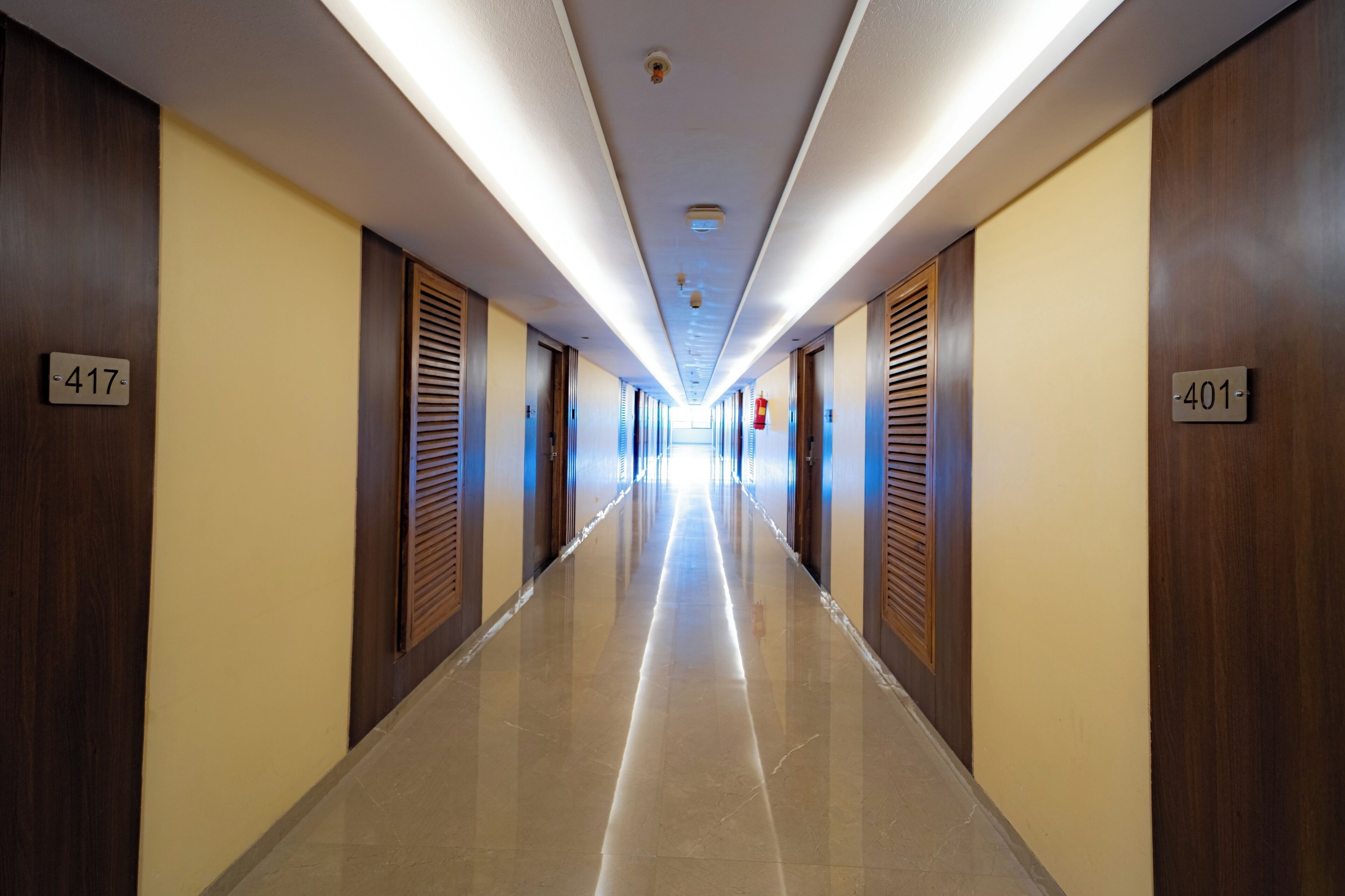 A hotel corridor with doors numbered 417 and 401, featuring wooden doors and a shiny tiled floor.
