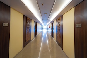 Un pasillo de hotel con puertas numeradas 417 y 401, con puertas de madera y un suelo de baldosas brillantes.