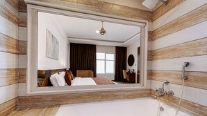 A hotel bathroom with a large mirror, a bathtub, and a shower.
