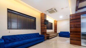 A modern living room with a blue sofa, a smaller sofa, and a TV mounted on the wall.