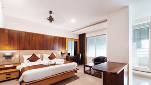 A modern hotel room with a large bed, a desk, and a large window.