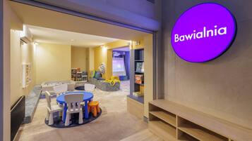 A children's play area with a round table, chairs, and a playpen.