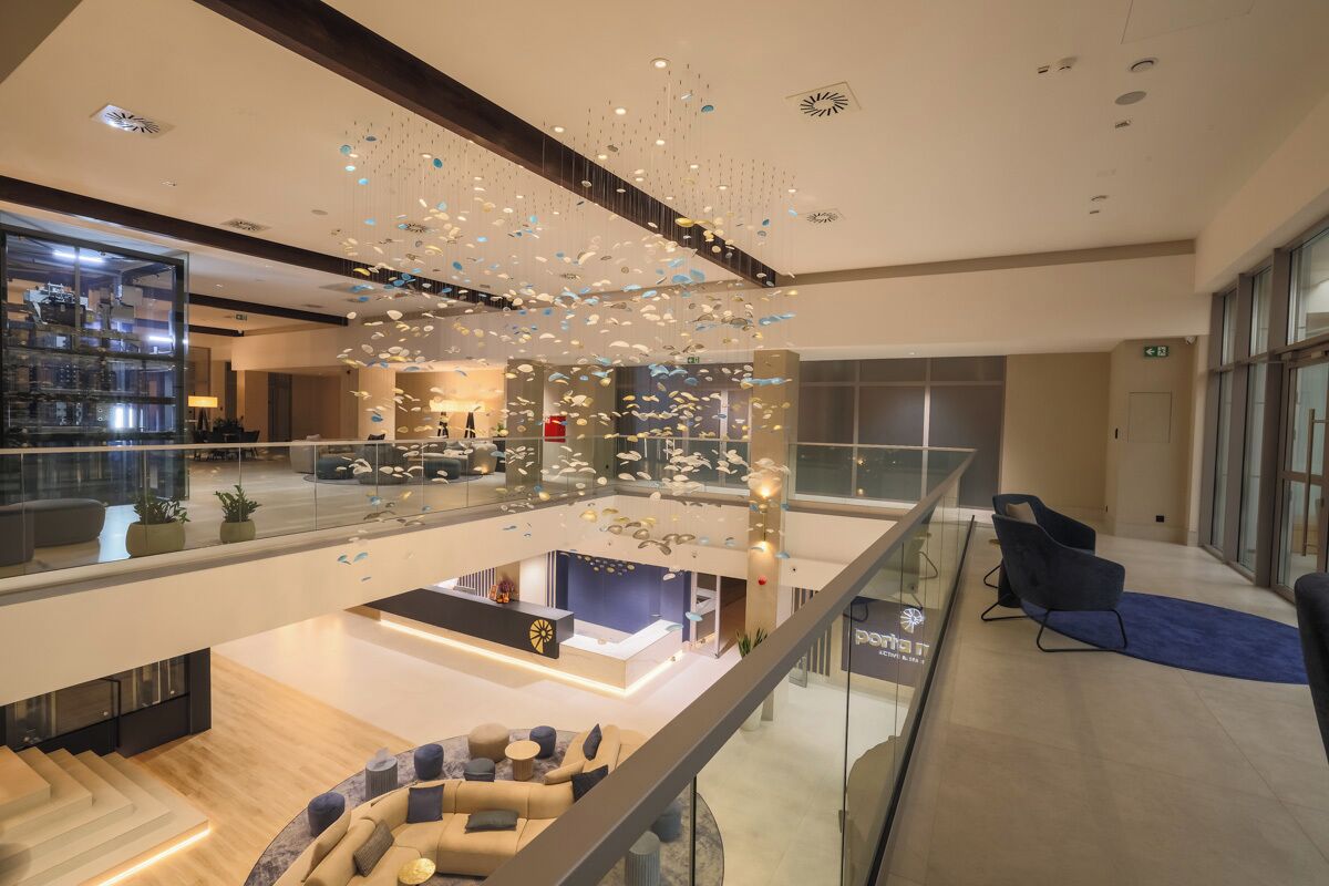 Eine moderne Hotelhalle mit Glastrennwand, einer Rezeption und einer Sitzecke mit Sofas.