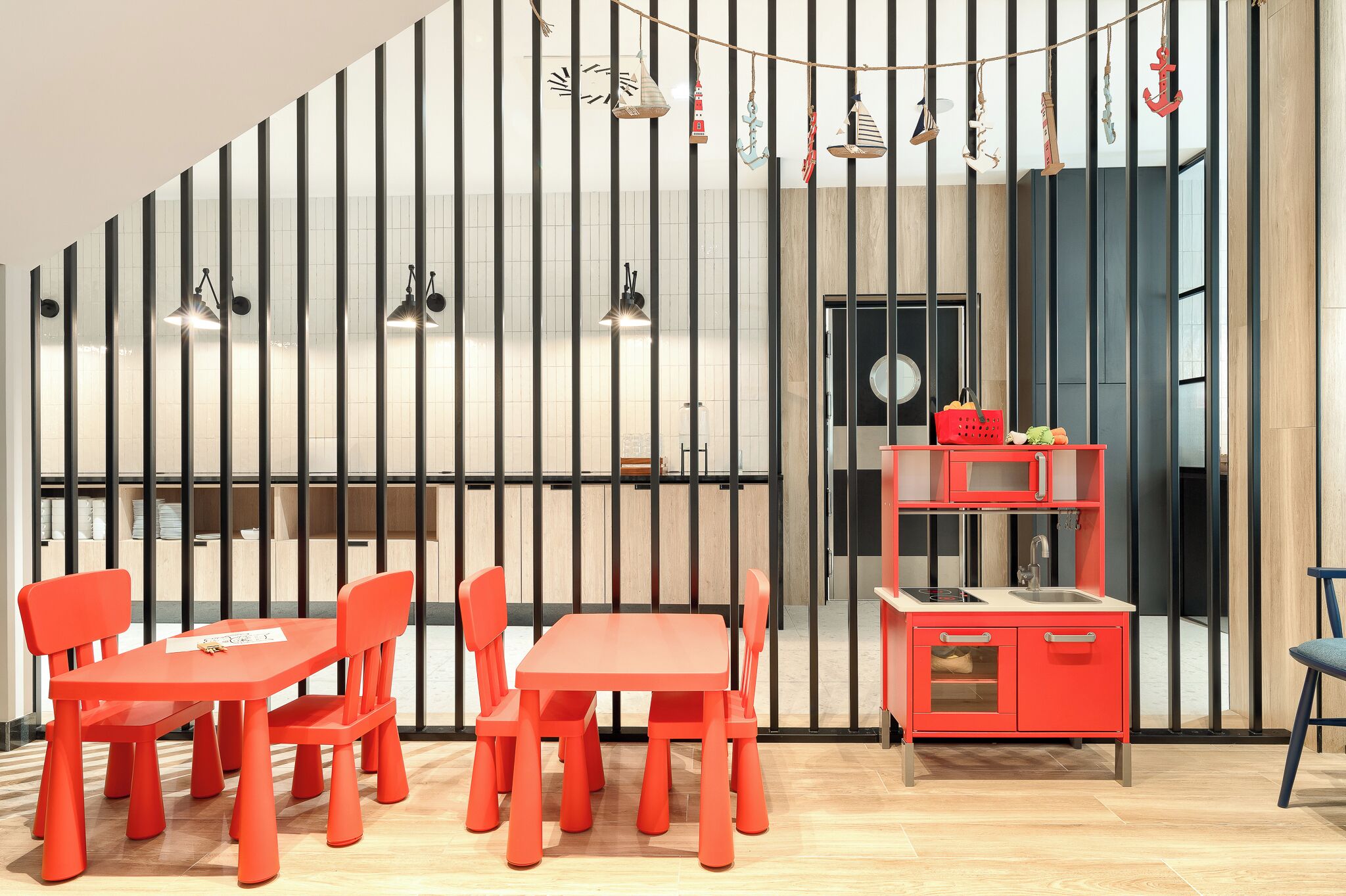 A modern kitchen with a red countertop and cabinets, a wooden floor, and a black and white striped wall.