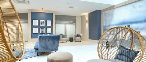 A modern lounge area with wicker chairs, a blue sofa, and a round table.