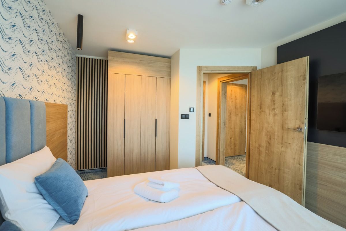 Ein Hotelzimmer mit einem Bett, einem Kleiderschrank und einer Tür zu einem weiteren Raum.