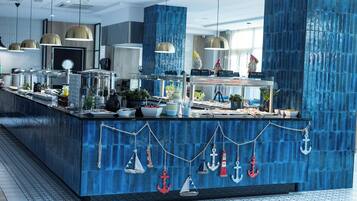A modern kitchen with blue tiles, hanging kitchen utensils, and a variety of food items on the counter.