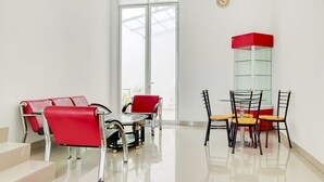 A modern hotel room with a glass partition, red and black chairs, a small table, and a staircase. - Hotel O Panakkukang Near Mall Panakkukang Formerly Golden White House (Makassar)